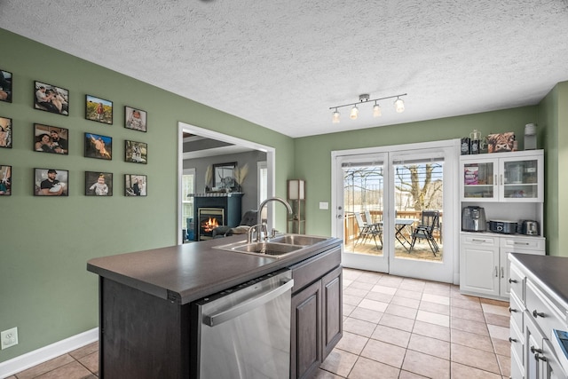 kitchen with dark countertops, dishwasher, a sink, and light tile patterned floors