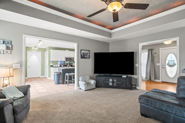 living area featuring a tray ceiling, crown molding, and light colored carpet