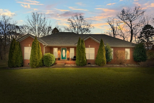 ranch-style house with crawl space, roof with shingles, a front lawn, and brick siding