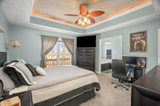 bedroom featuring carpet, a raised ceiling, a textured ceiling, and ensuite bath