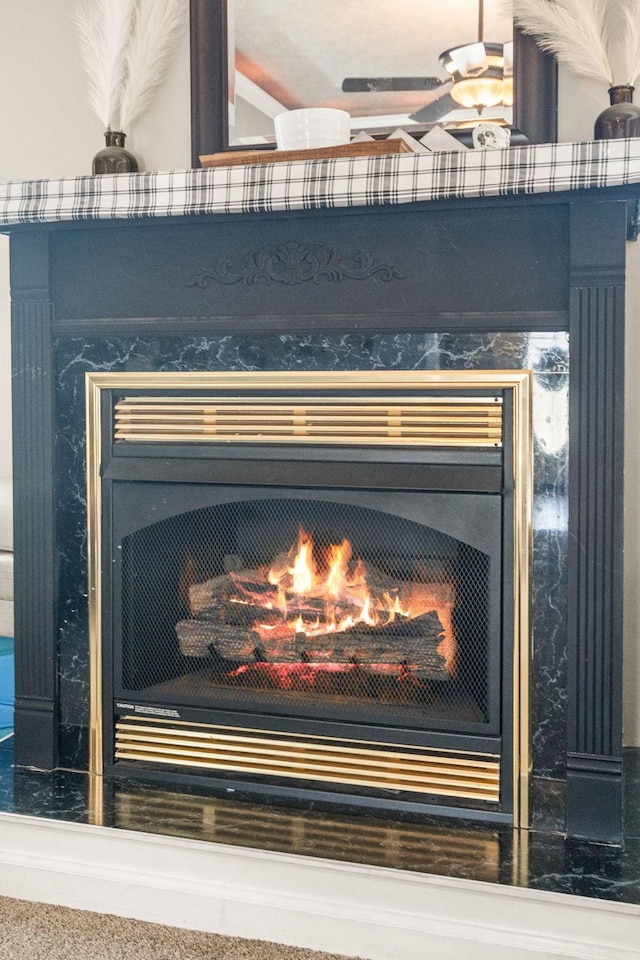 room details with ceiling fan and a lit fireplace