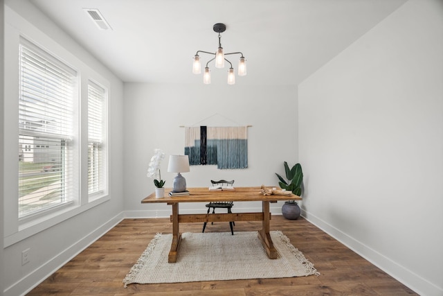 office space featuring an inviting chandelier, baseboards, visible vents, and wood finished floors