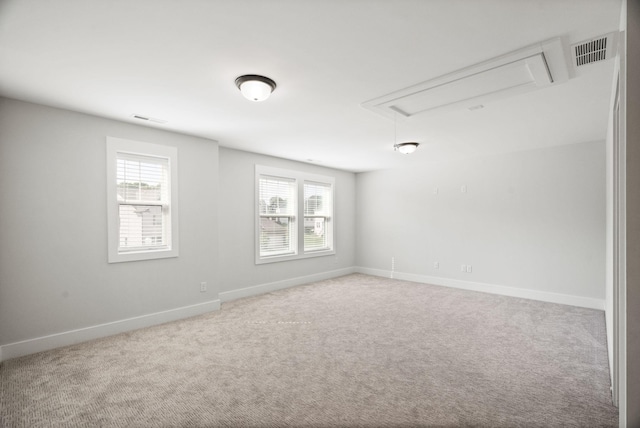 spare room with attic access, a healthy amount of sunlight, visible vents, and carpet flooring