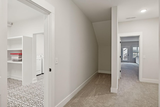 hall with light carpet, baseboards, visible vents, and independent washer and dryer