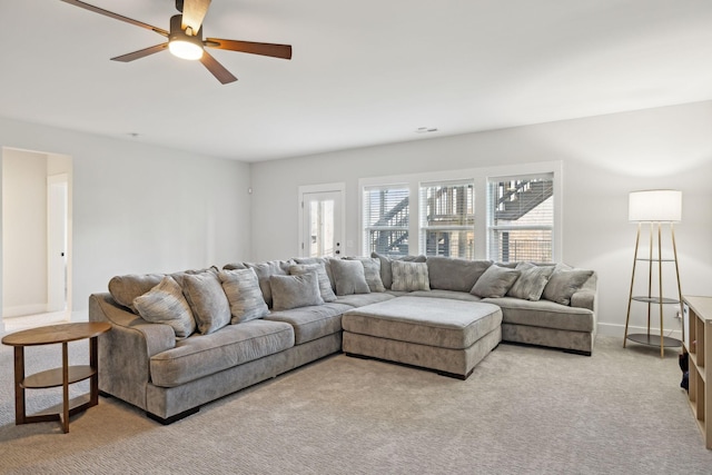 living area featuring a ceiling fan, light colored carpet, and baseboards