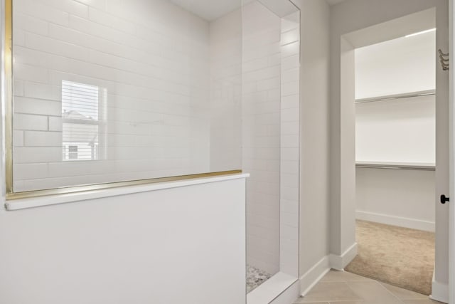 bathroom with tile patterned floors, a walk in closet, baseboards, and walk in shower