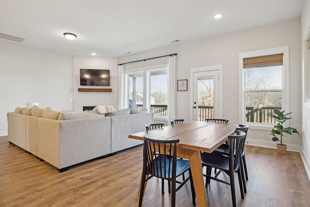 dining space featuring light wood finished floors, baseboards, visible vents, a fireplace, and recessed lighting