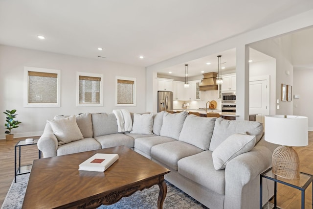 living area with light wood-type flooring, baseboards, and recessed lighting