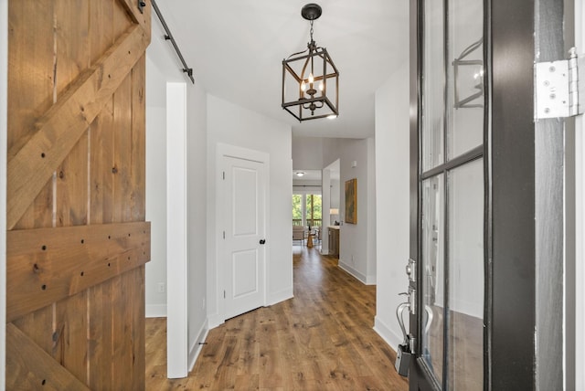 interior space with a barn door, wood finished floors, and baseboards