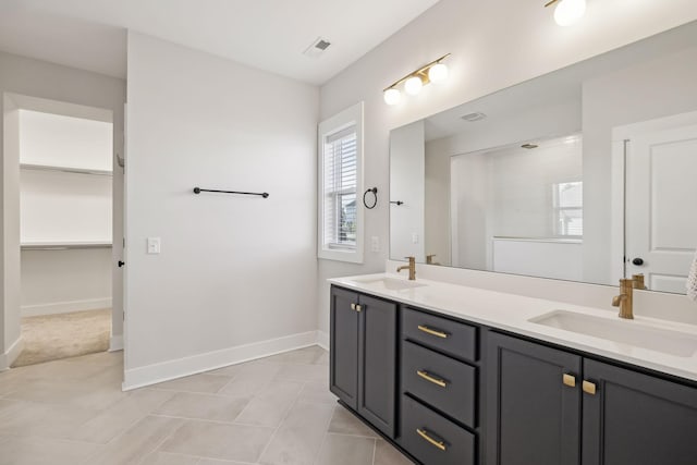 full bath with double vanity, a sink, visible vents, and baseboards