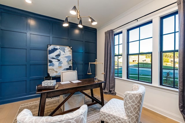 office area featuring ornamental molding, light wood-type flooring, a decorative wall, and baseboards