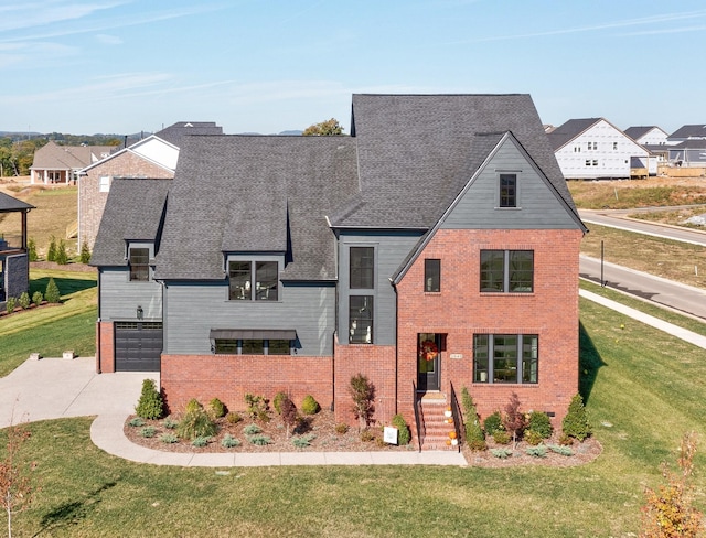 view of front of house featuring an attached garage, concrete driveway, brick siding, and a front yard