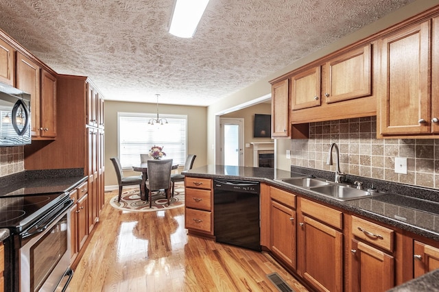 kitchen featuring visible vents, brown cabinetry, appliances with stainless steel finishes, light wood-type flooring, and a sink