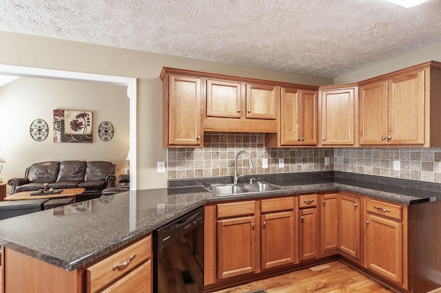 kitchen with black dishwasher, light wood finished floors, backsplash, and a sink