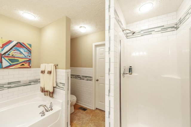 full bath featuring a garden tub, toilet, visible vents, tile walls, and a shower stall