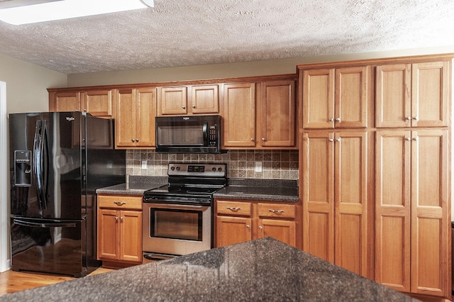 kitchen with tasteful backsplash, brown cabinets, a textured ceiling, and black appliances