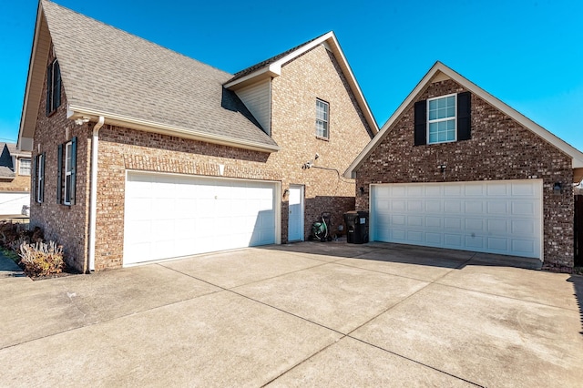 view of front of home with a garage, brick siding, and roof with shingles