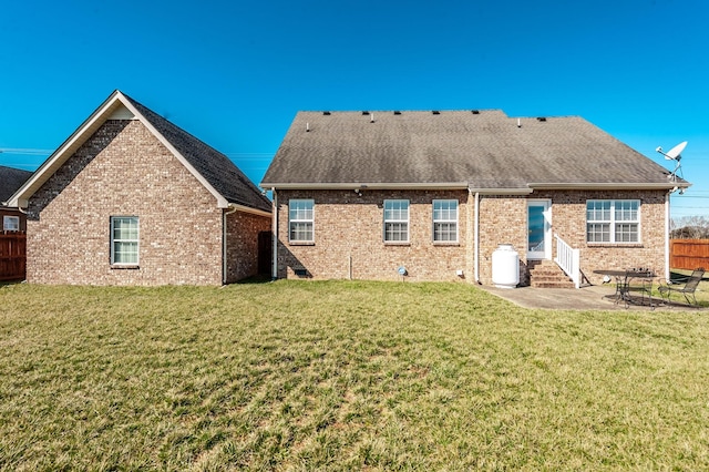 rear view of house featuring entry steps, a yard, and fence