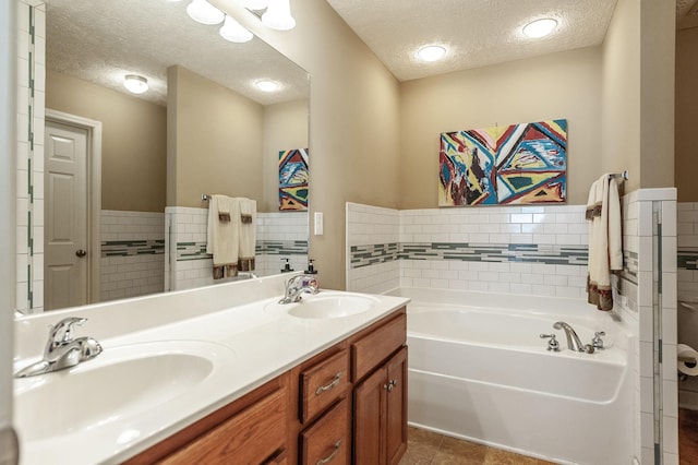 bathroom featuring a garden tub, a textured ceiling, and a sink