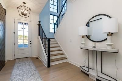 foyer featuring stairs, a notable chandelier, wood finished floors, and baseboards