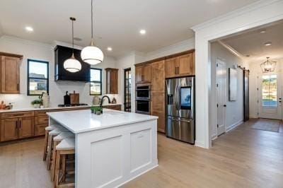 kitchen featuring light countertops, appliances with stainless steel finishes, brown cabinetry, and decorative light fixtures