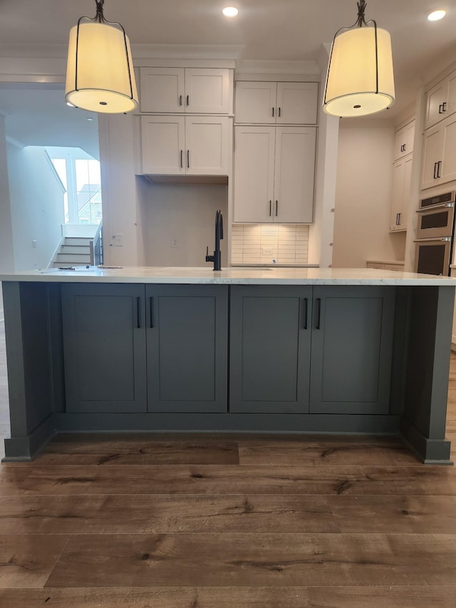 kitchen featuring tasteful backsplash, white cabinets, dark wood-type flooring, and decorative light fixtures