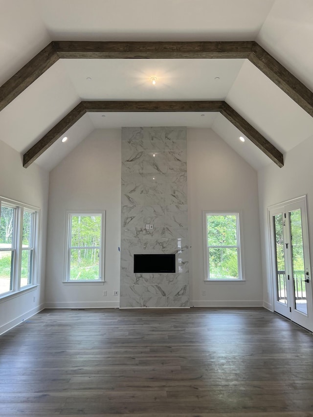 unfurnished living room featuring wood finished floors, a wealth of natural light, and baseboards