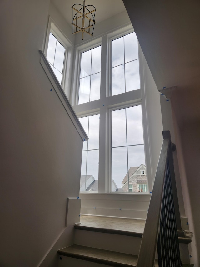 staircase featuring a towering ceiling and an inviting chandelier