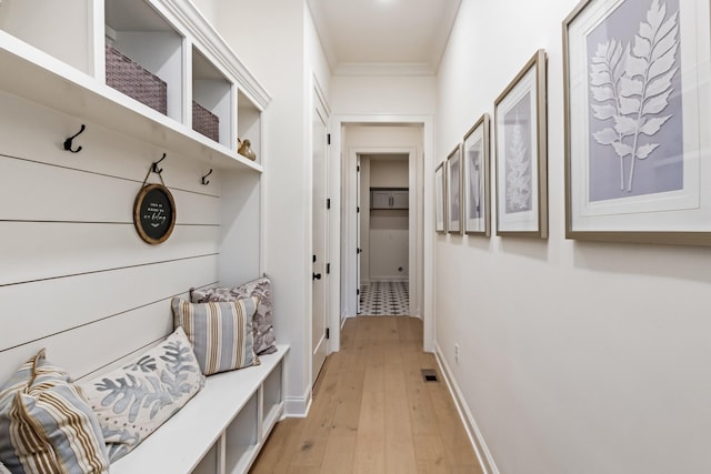 mudroom with light wood-type flooring, crown molding, and baseboards