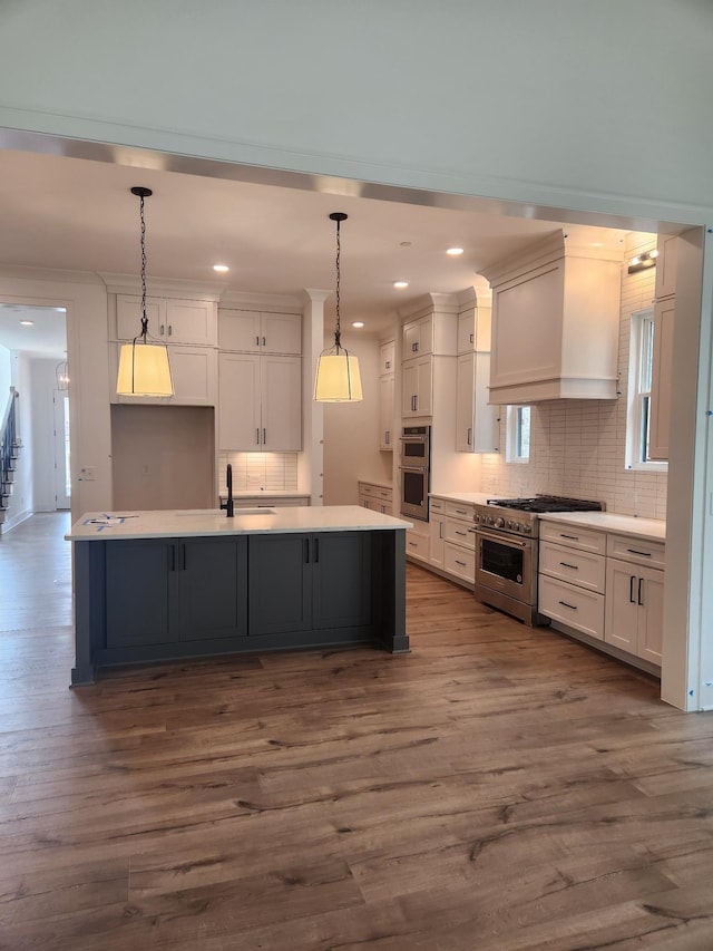 kitchen featuring appliances with stainless steel finishes, custom range hood, dark wood finished floors, and white cabinetry