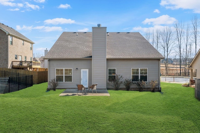 rear view of house featuring a shingled roof, fence, a lawn, a chimney, and a patio area