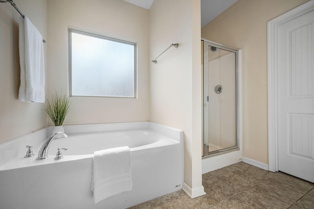 full bathroom featuring a stall shower, a garden tub, and baseboards