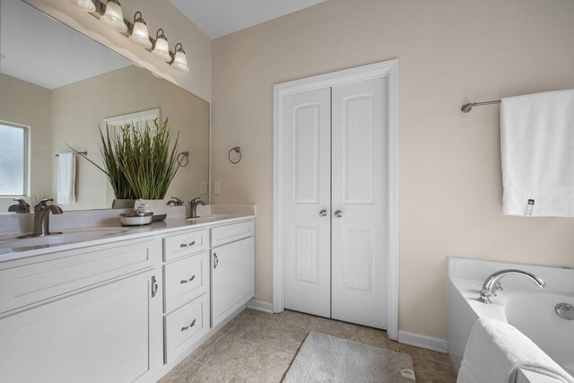 full bathroom featuring a garden tub, double vanity, a sink, and baseboards