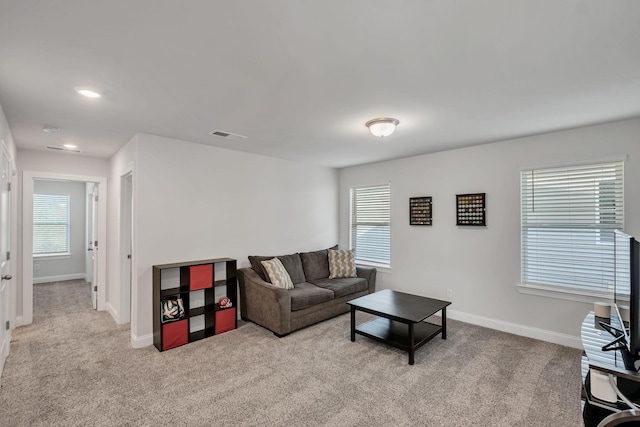 living room with visible vents, baseboards, and light colored carpet