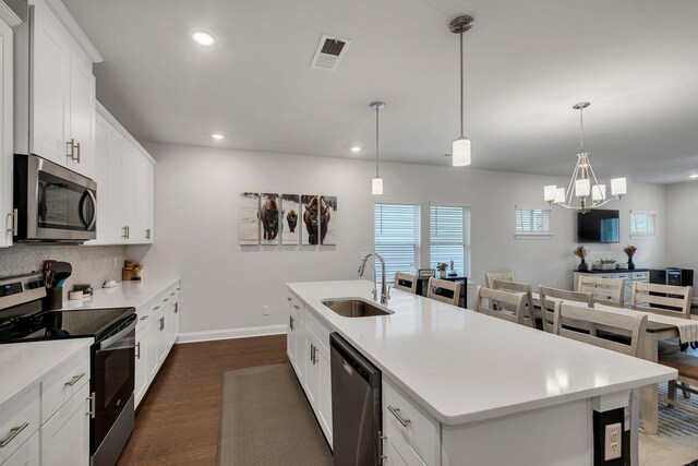 kitchen with dark wood-style flooring, a sink, light countertops, appliances with stainless steel finishes, and backsplash