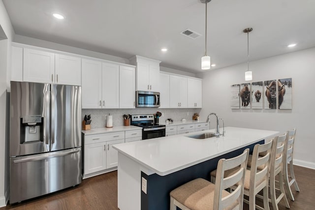 kitchen featuring tasteful backsplash, appliances with stainless steel finishes, dark wood finished floors, and a sink