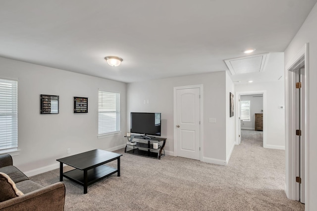 carpeted living room with attic access and baseboards