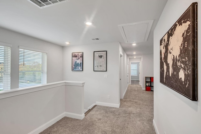 corridor featuring carpet floors, visible vents, attic access, an upstairs landing, and baseboards