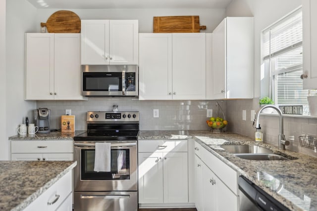 kitchen featuring appliances with stainless steel finishes, a healthy amount of sunlight, a sink, and backsplash