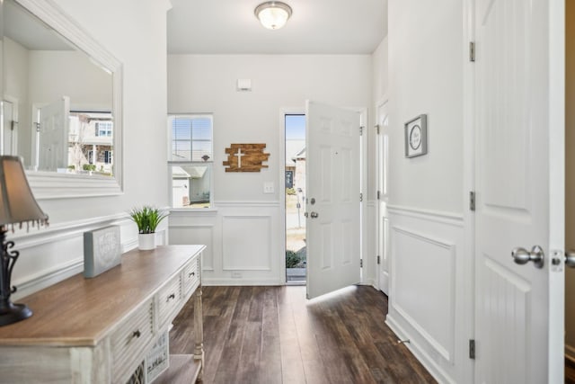 entrance foyer featuring dark wood-style flooring, a wainscoted wall, and a decorative wall