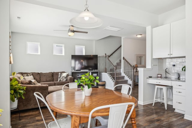 dining area with dark wood-style floors, stairs, a ceiling fan, and baseboards