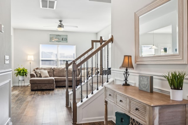 stairs with wood finished floors, visible vents, and a ceiling fan