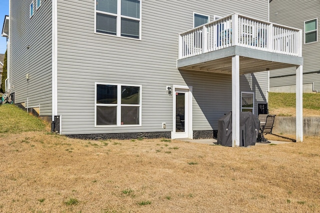 rear view of house featuring a wooden deck and a yard