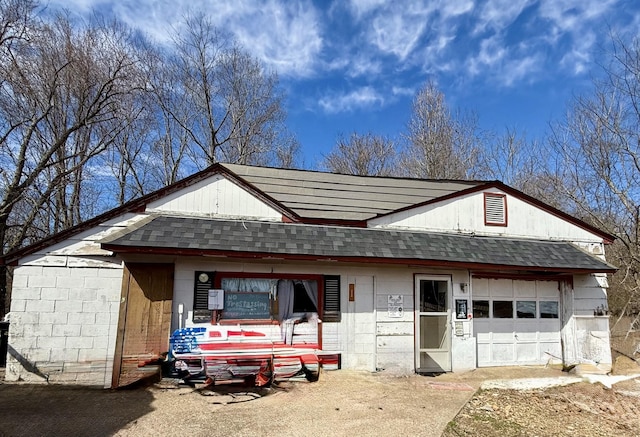 view of front facade featuring a shingled roof, concrete block siding, and an attached garage