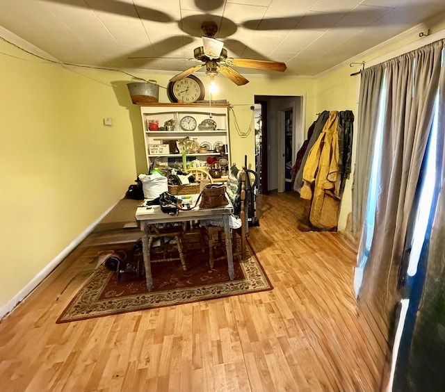 dining space with wood finished floors, a ceiling fan, and baseboards