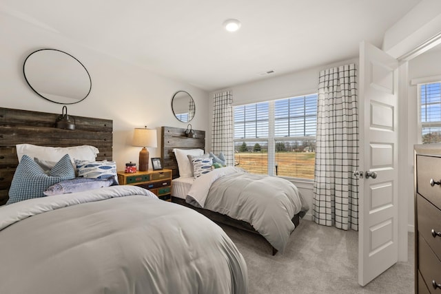 bedroom featuring multiple windows, visible vents, and light colored carpet