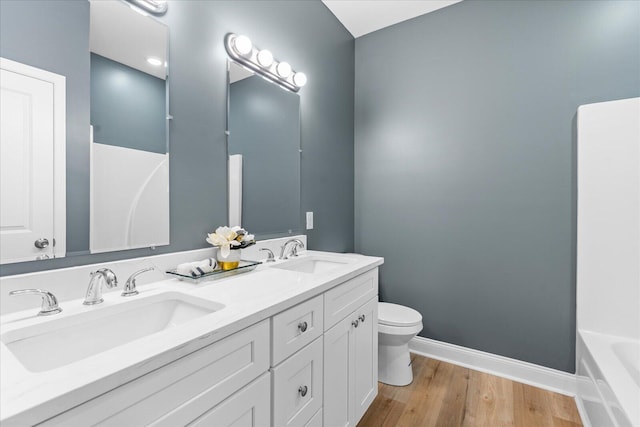 full bathroom with toilet, baseboards, a sink, and wood finished floors