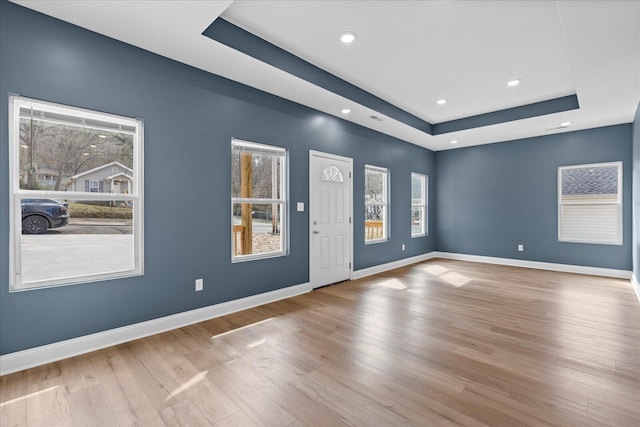 unfurnished room with baseboards, a tray ceiling, and a wealth of natural light