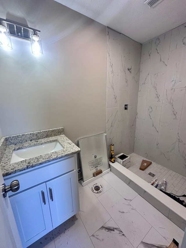 bathroom featuring a stall shower, marble finish floor, a textured ceiling, and vanity