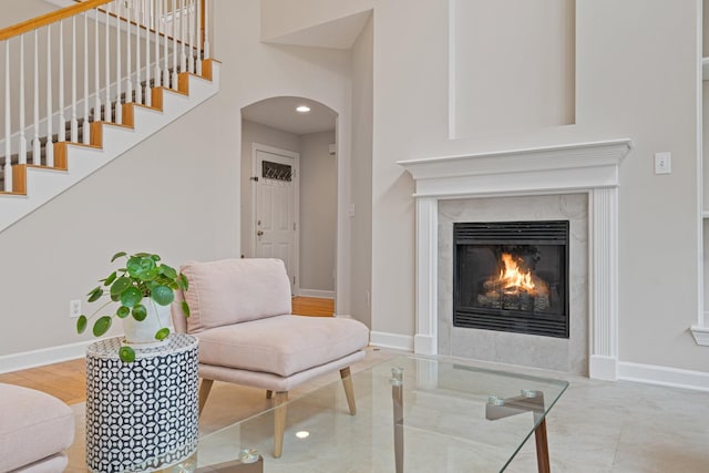 interior space featuring a high end fireplace, arched walkways, baseboards, and stairs